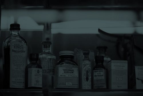 a dark image of old pharmacy medication bottles