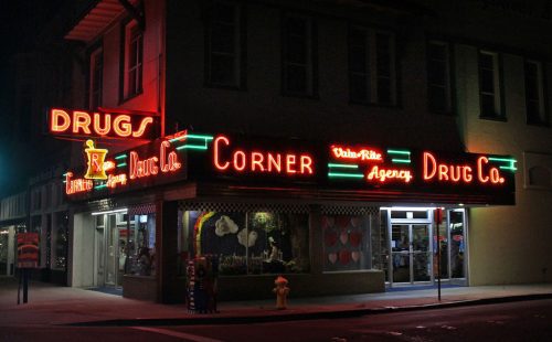 the Corner Drug Co neon sign all lit up at night