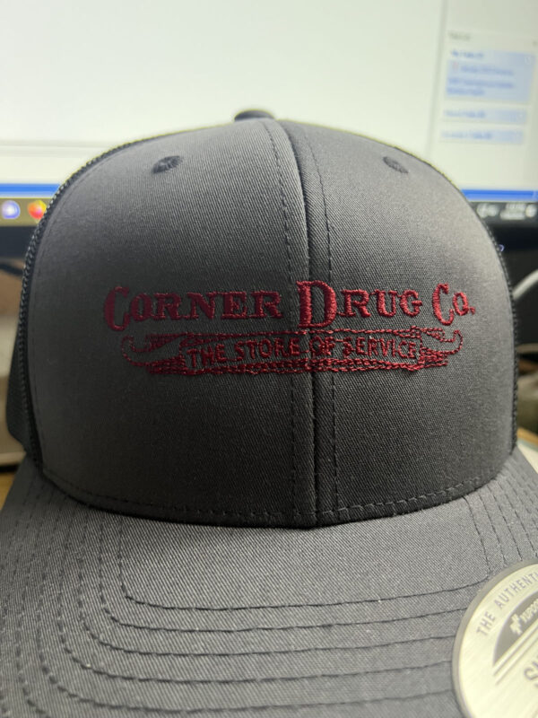 A black baseball cap with the logo Corner Drug Co embroidered on the front.