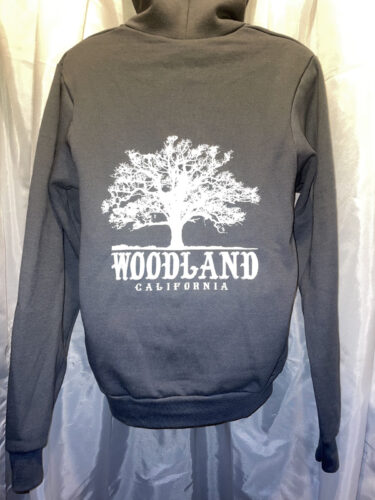 The back of a black hooded pullover sweatshirt with a white Woodland logo featuring a silhouette of a large tree