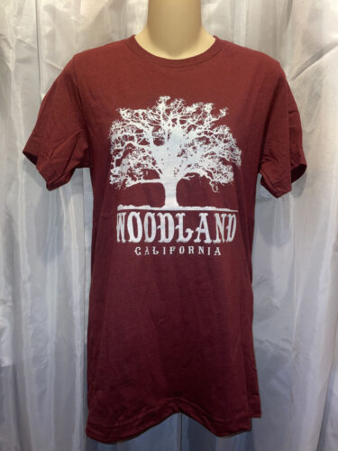 A burgundy t-shirt with a large white Woodland logo featuring a silhouette of a tree