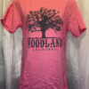 A salmon colored t-shirt with a large black Woodland logo featuring a silhouette of a tree